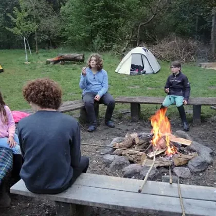 Kinder sitzen um ein Lagerfeuer