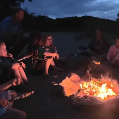 Kinder sitzen um ein Lagerfeuer bei Nacht