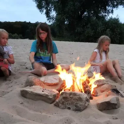 Kinder sitzen beim Lagerfeuer am Strand