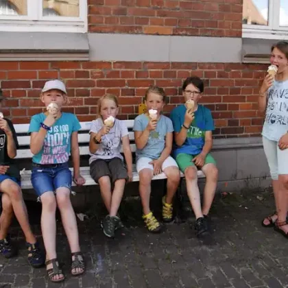 Kinder sitzen auf einer Bank und essen Eis