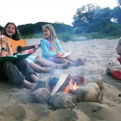 Kinder mit Gitarre beim Lagerfeuer am Strand