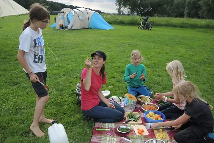 Betreuerin und Kinder beim Essen auf dem Rasen