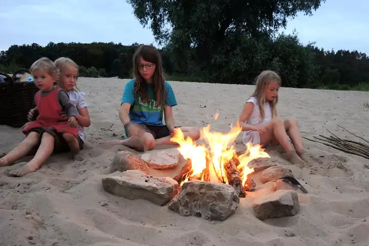 Kinder sitzen beim Lagerfeuer am Strand