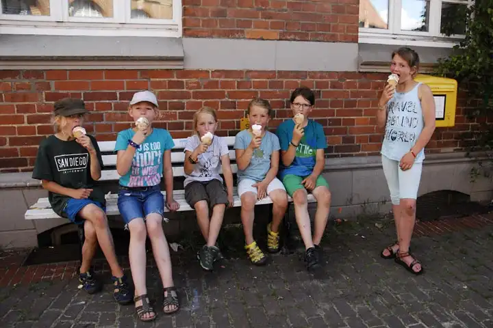 Kinder sitzen auf einer Bank und essen Eis